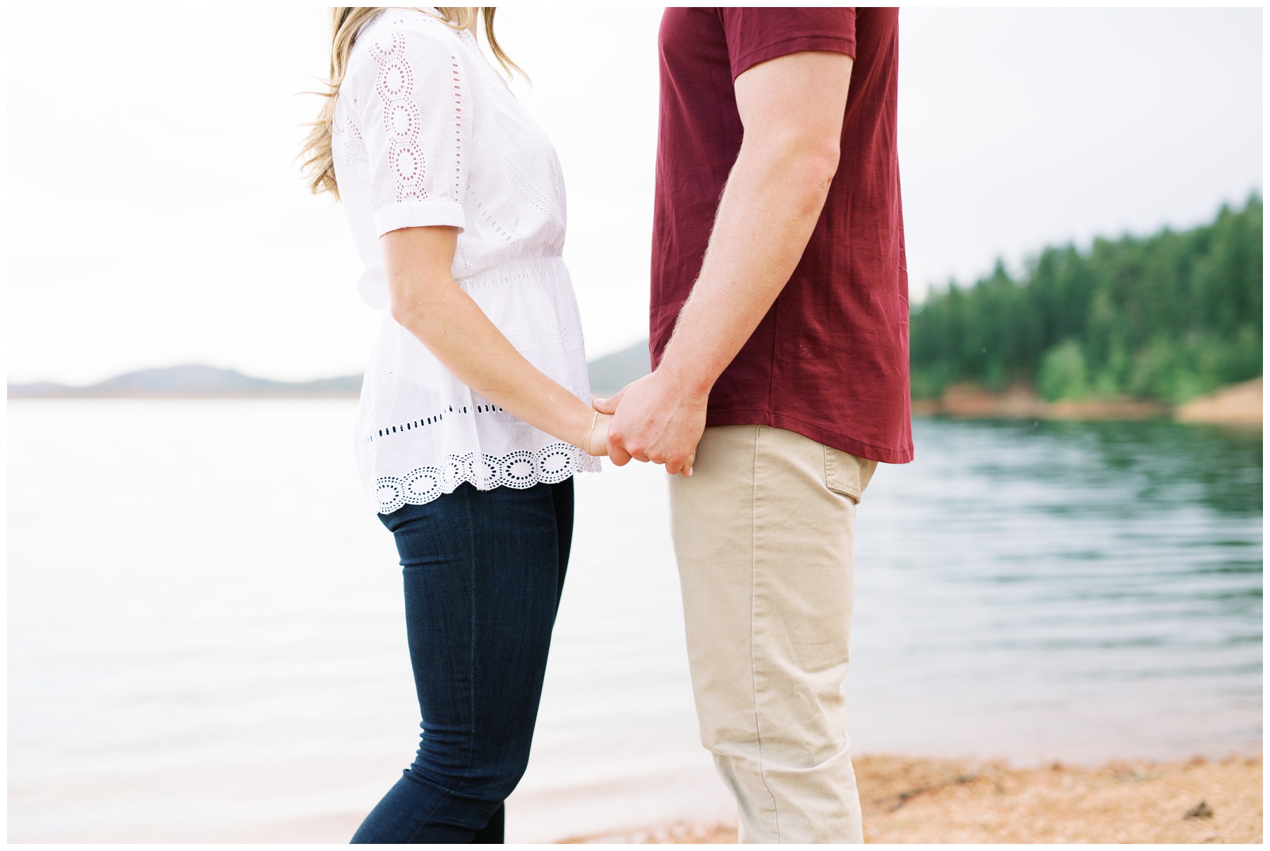 Engagement photo by the water holding hands Colorado | Cat Murphy Photography