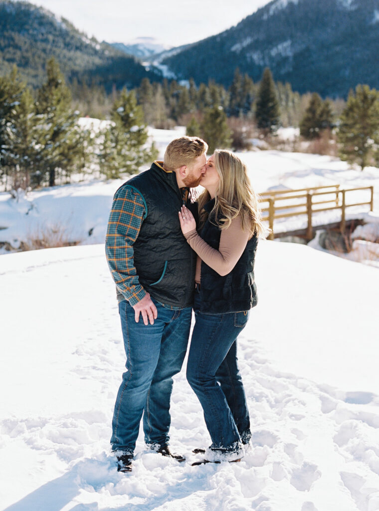 Engaged couple poses in the snow with smiles during Vail, Colorado winter photo shoot.