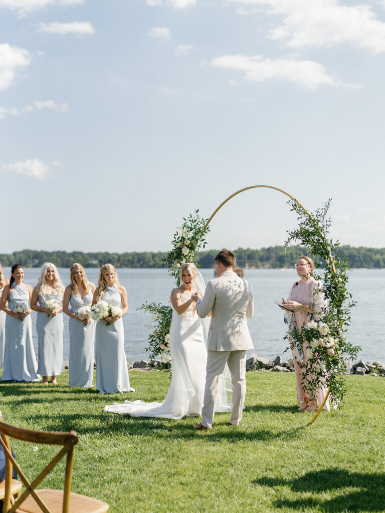 A stunning photo of a bride and groom holding hands and walking down the aisle to start their new life together, with the private estate and serene lake in the background.