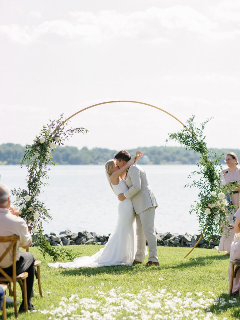 A stunning photo of a bride and groom holding hands and walking down the aisle to start their new life together, with the private estate and serene lake in the background.