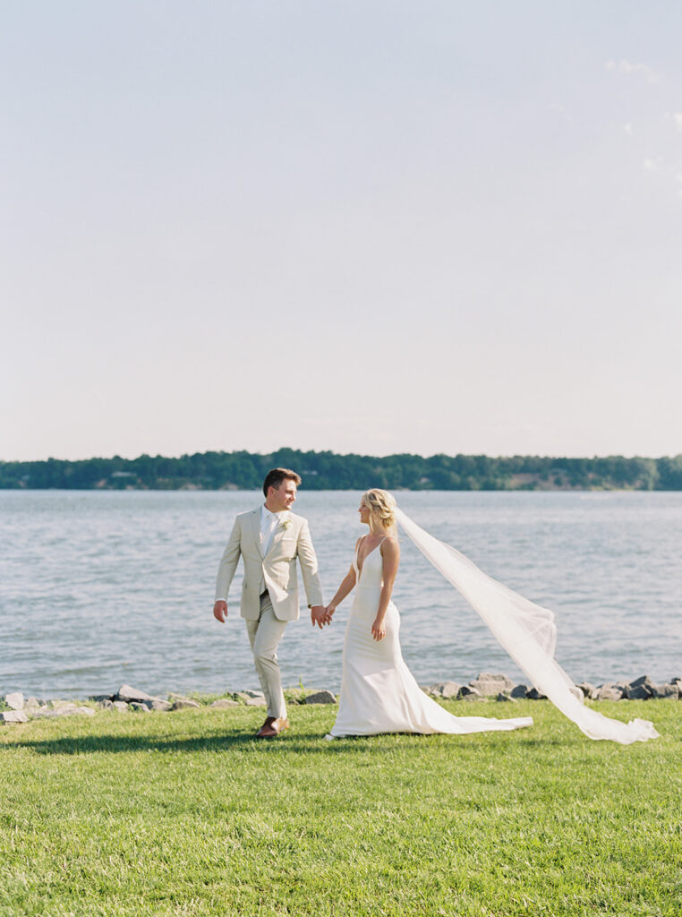 A breathtaking view of the lakefront wedding ceremony at a private estate in Maryland, with the happy couple and their guests celebrating in a beautiful natural setting.