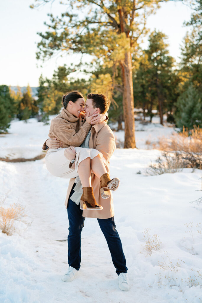 A romantic photo of a couple cuddling up to each other on a chilly winter day, with the stunning view of the Front Range mountains in the background.