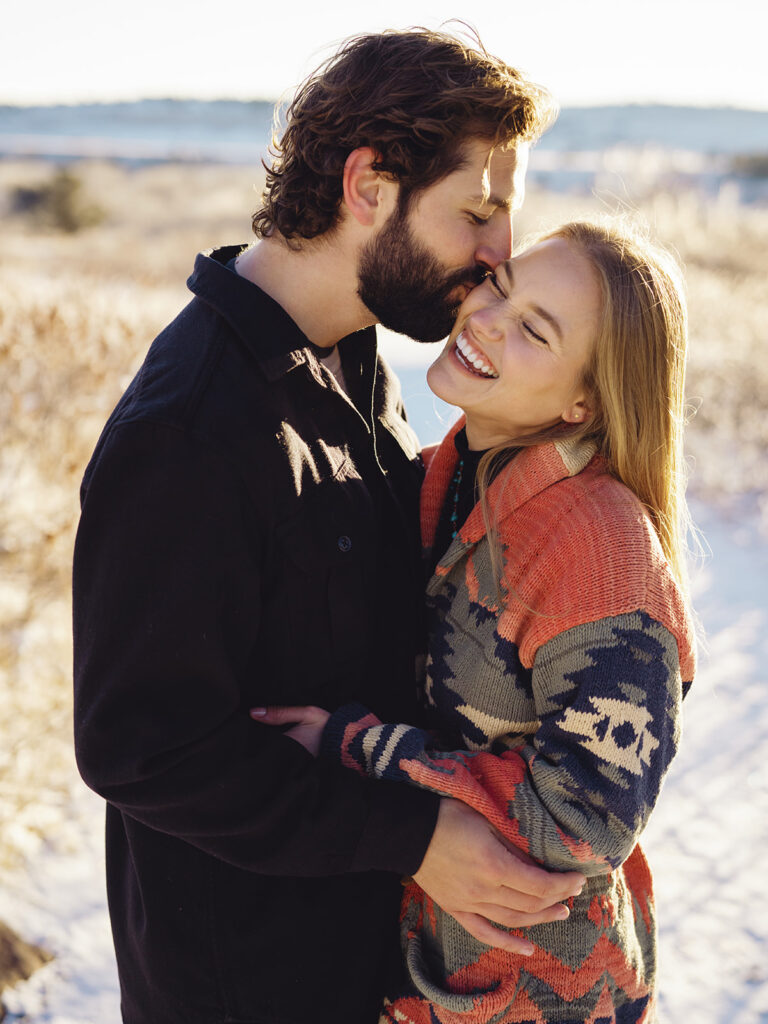 A beautiful moment captured as two people embrace each other, their eyes closed as they enjoy the winter morning's warmth and the scenic view.