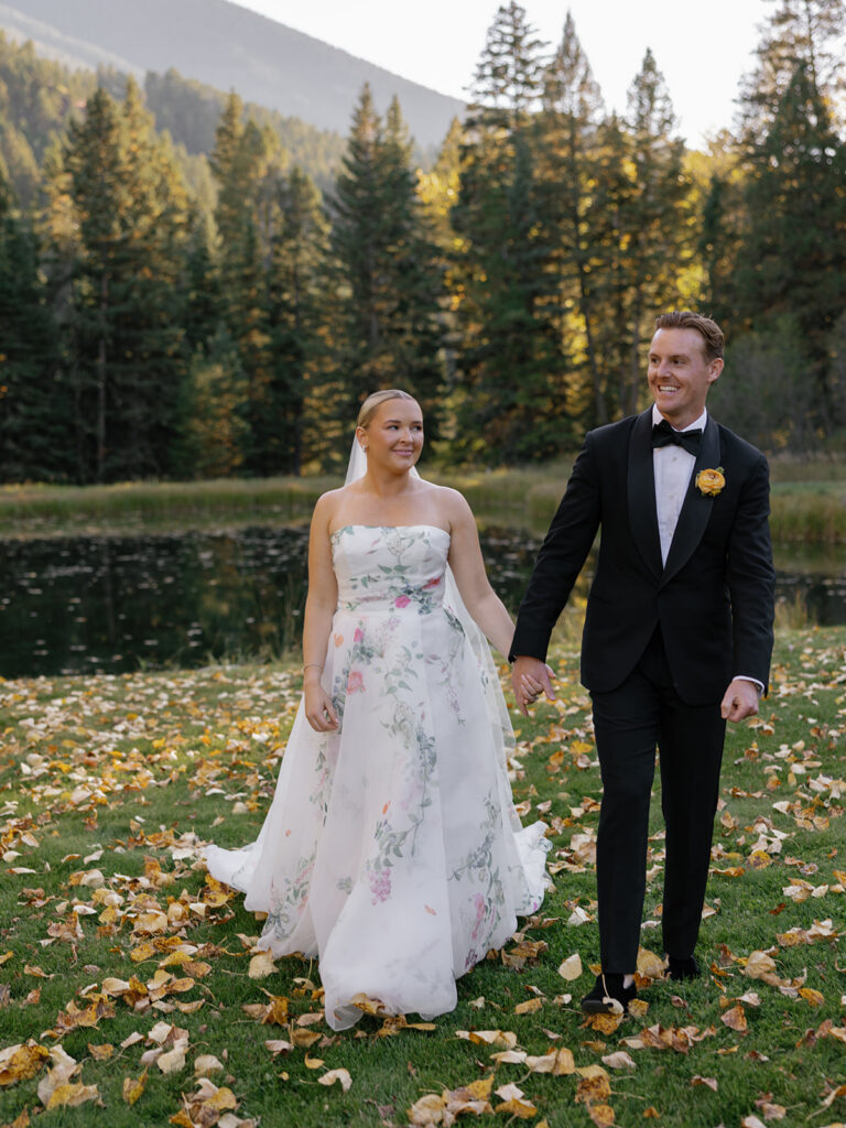 bride and groom walking through fall leaves at Montana ranch wedding