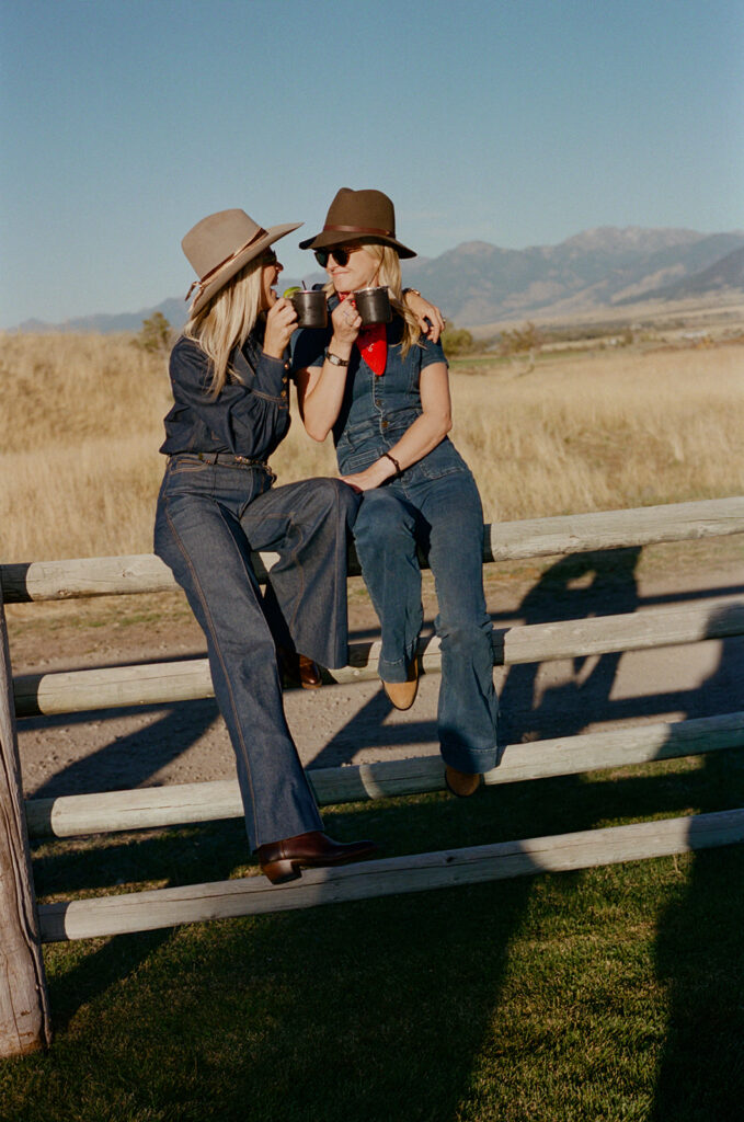 guests sitting on fence during welcome party at Montana ranch wedding