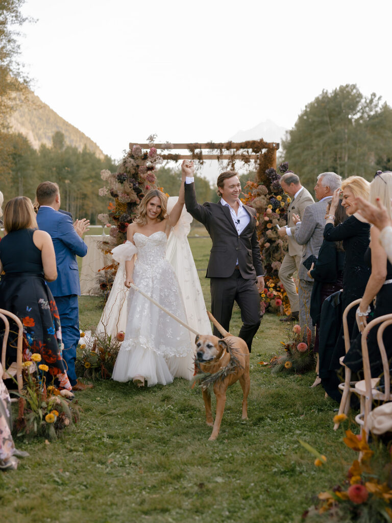 couple walking down aisle with dog at Aspen wedding