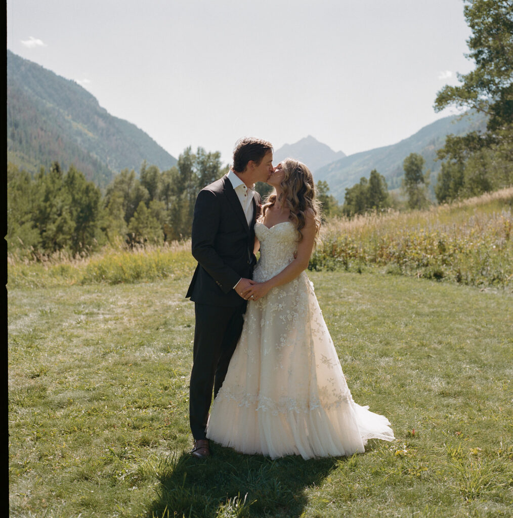 bride and groom walking through Aspen field with mountain views