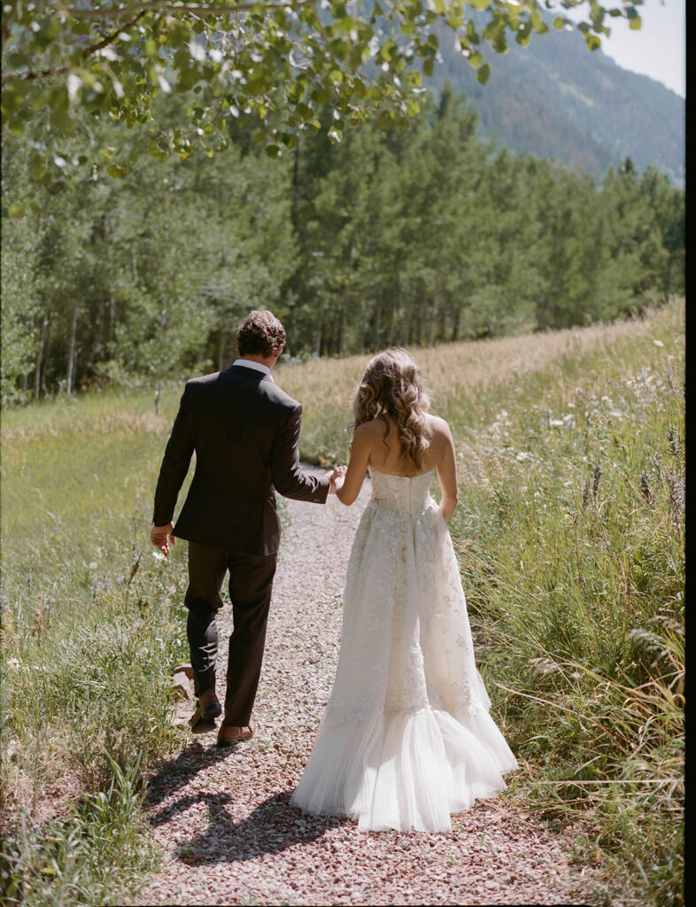 bride and groom walking through Aspen field with mountain views