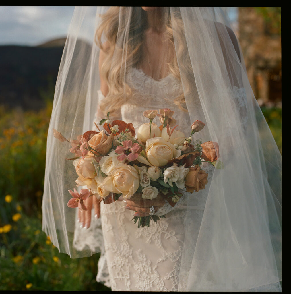 Bride holding bouquet under veil in Aspen fall landscape