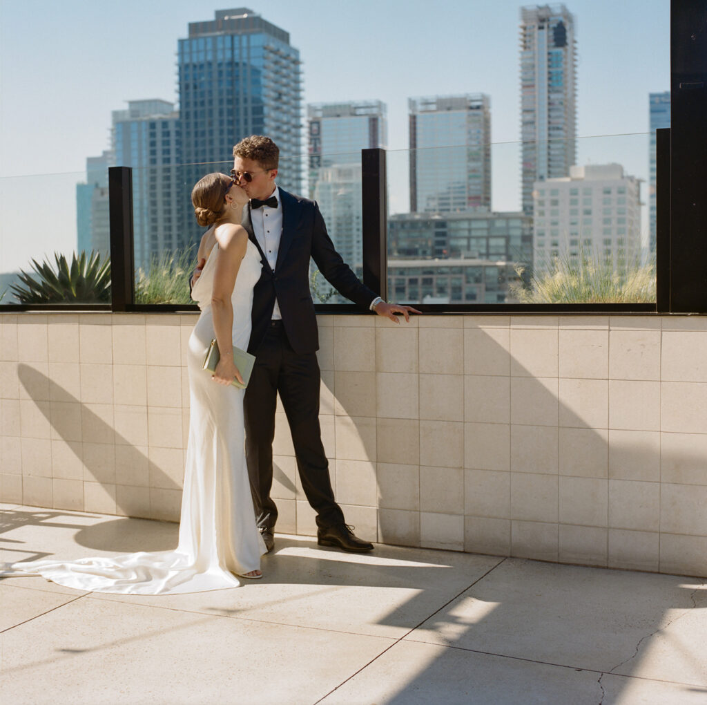 couple kissing on rooftop with downtown LA skyline